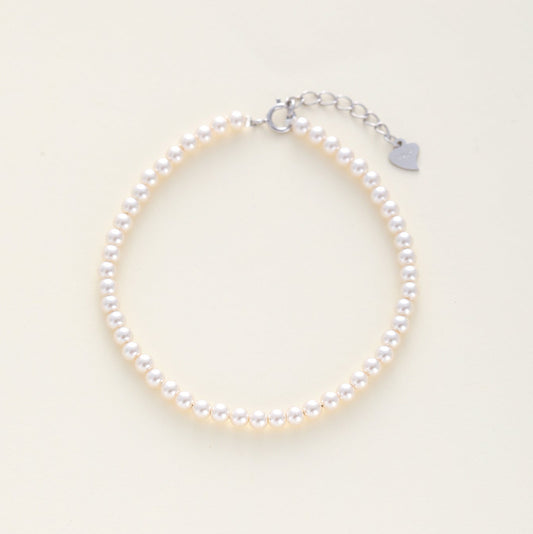 A minimalist bridal pearl beaded bracelet with a silver lobster clasp and an adjustable silver chain extender