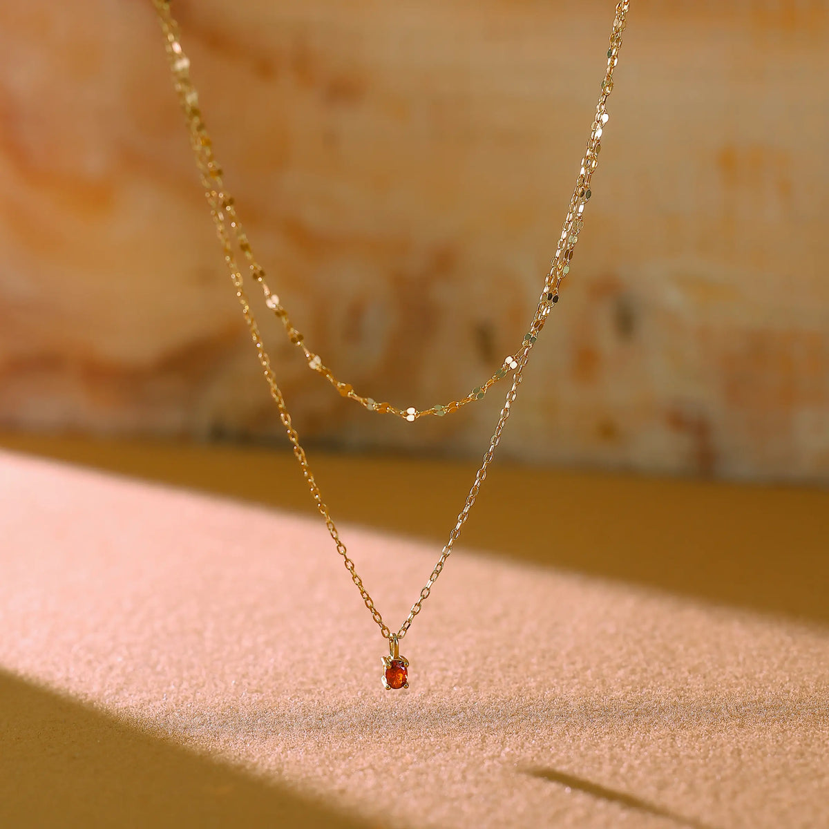 Close up of red cubic zirconia crystal pendant in 4-prong gold setting.