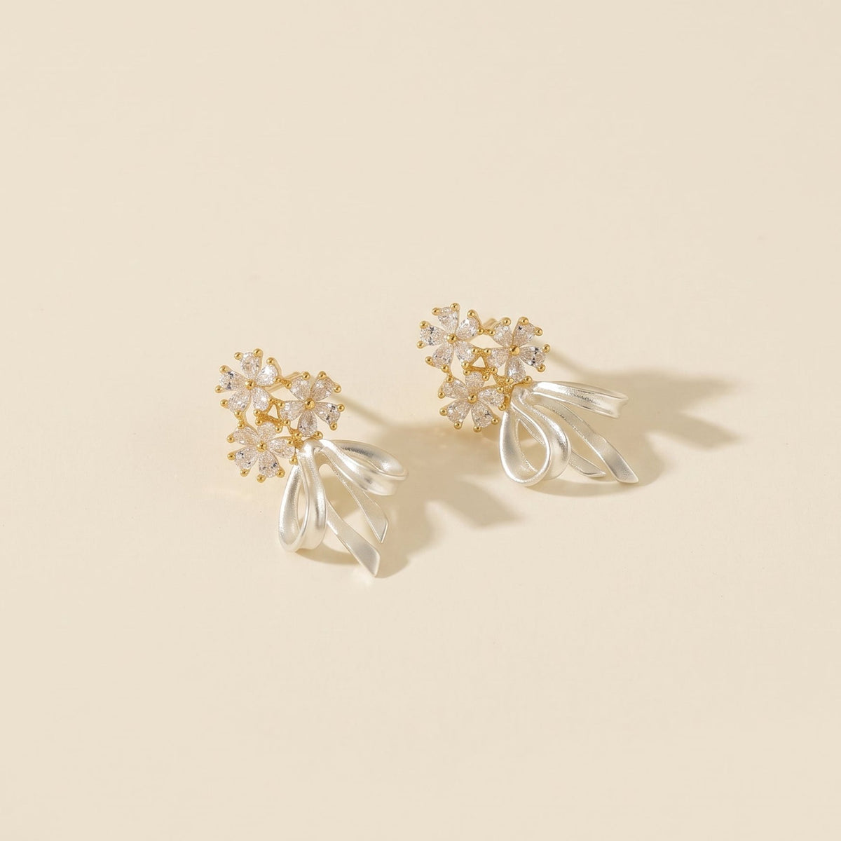 A pair of gold cz floral stud earrings with a white bow