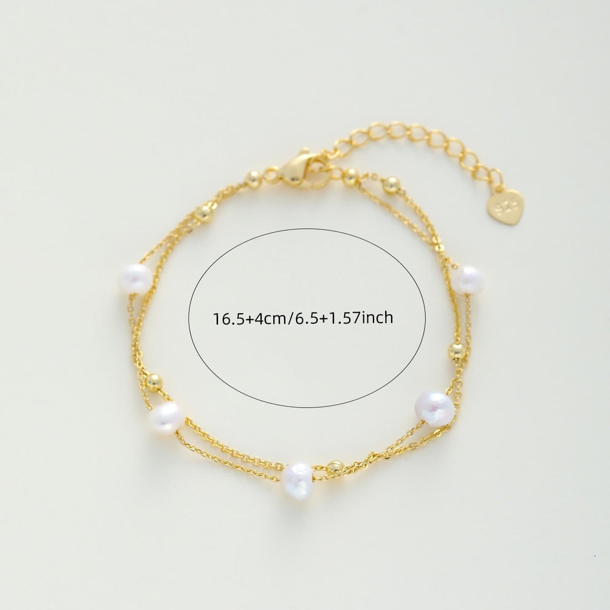 A delicate gold double-strand chain bracelet with white freshwater pearls, displayed on a light off-white background with a size overlay indicating 16.5+4cm (6.