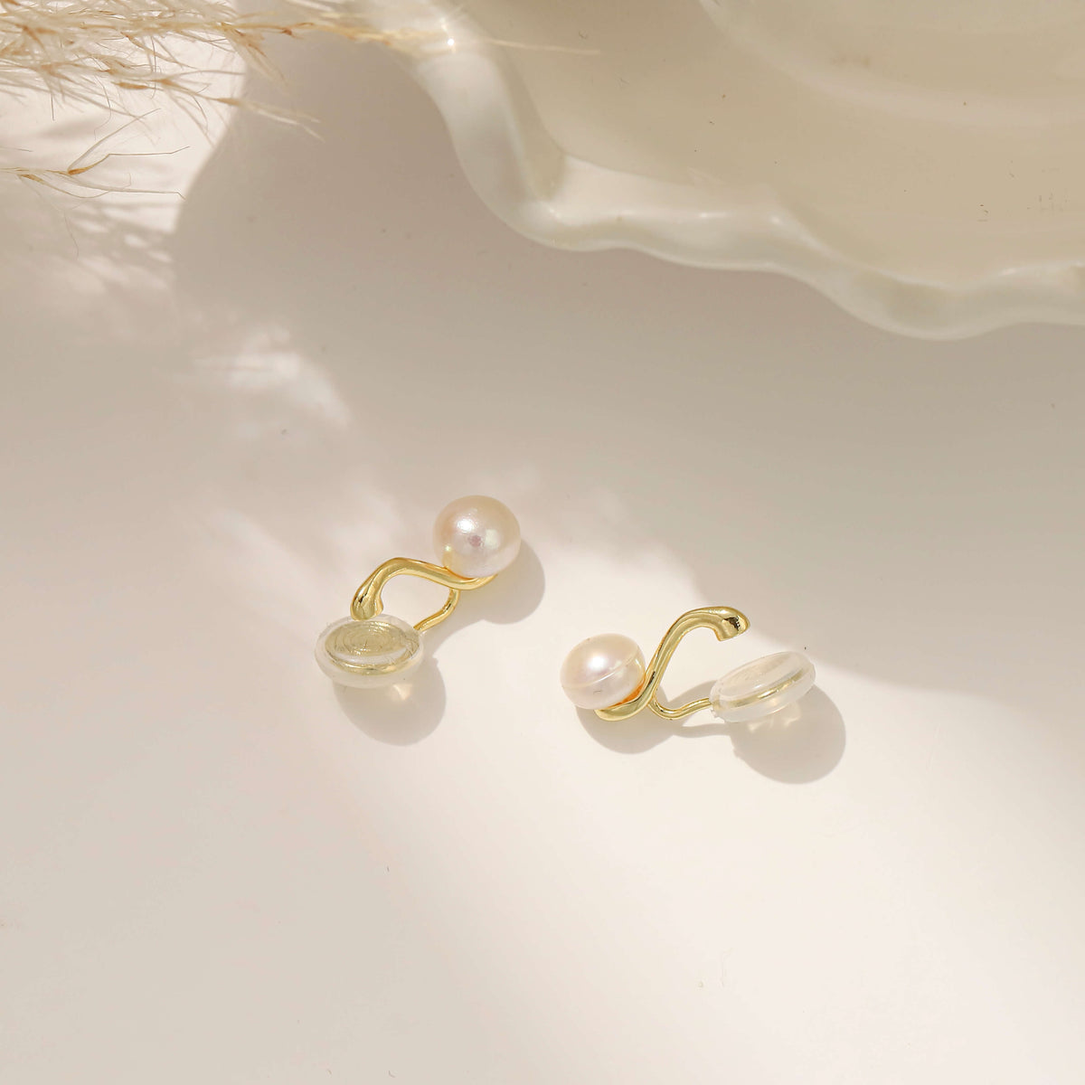 A pair of gold clip on earrings with a single white pearl 