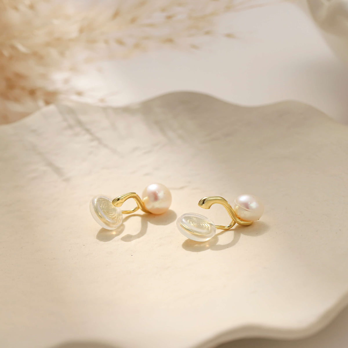 A pair of gold freshwater pearl clip on earrings showing the mechanism of the pinch free clip on for non pierced ears