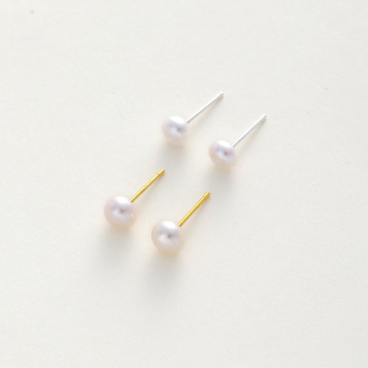 pearl stud earrings with gold and silver posts on a clean, off-white background.
