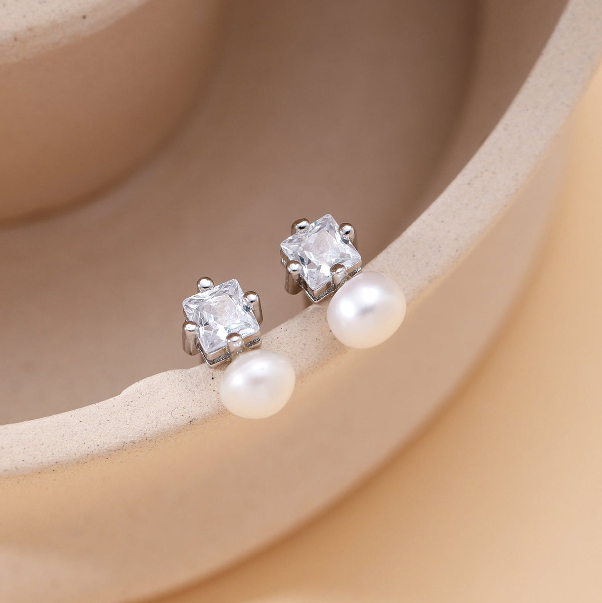 A pair of minimalist sterling silver CZ and pearl stud earrings