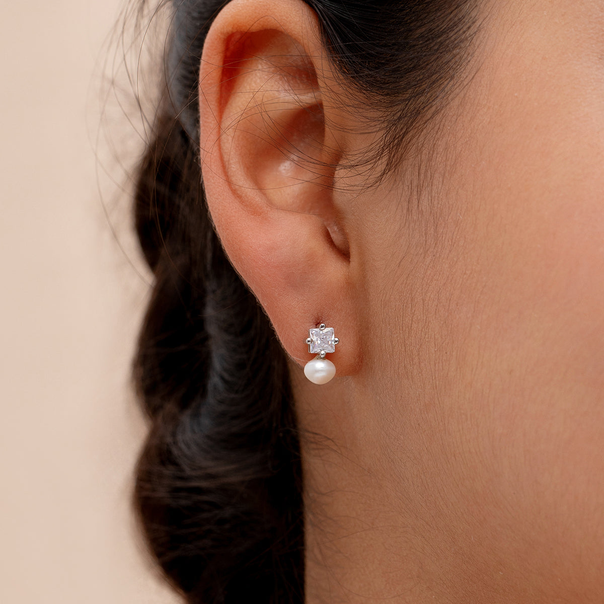 close up of model wearing minimalist 925 silver ear studs with pearl and cz