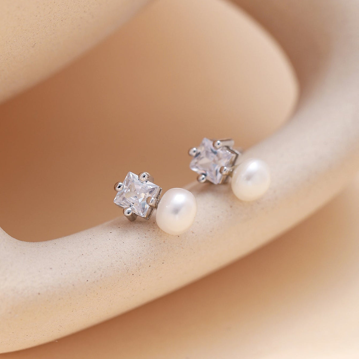 A pair of stud earrings with silver-toned cz and pearls