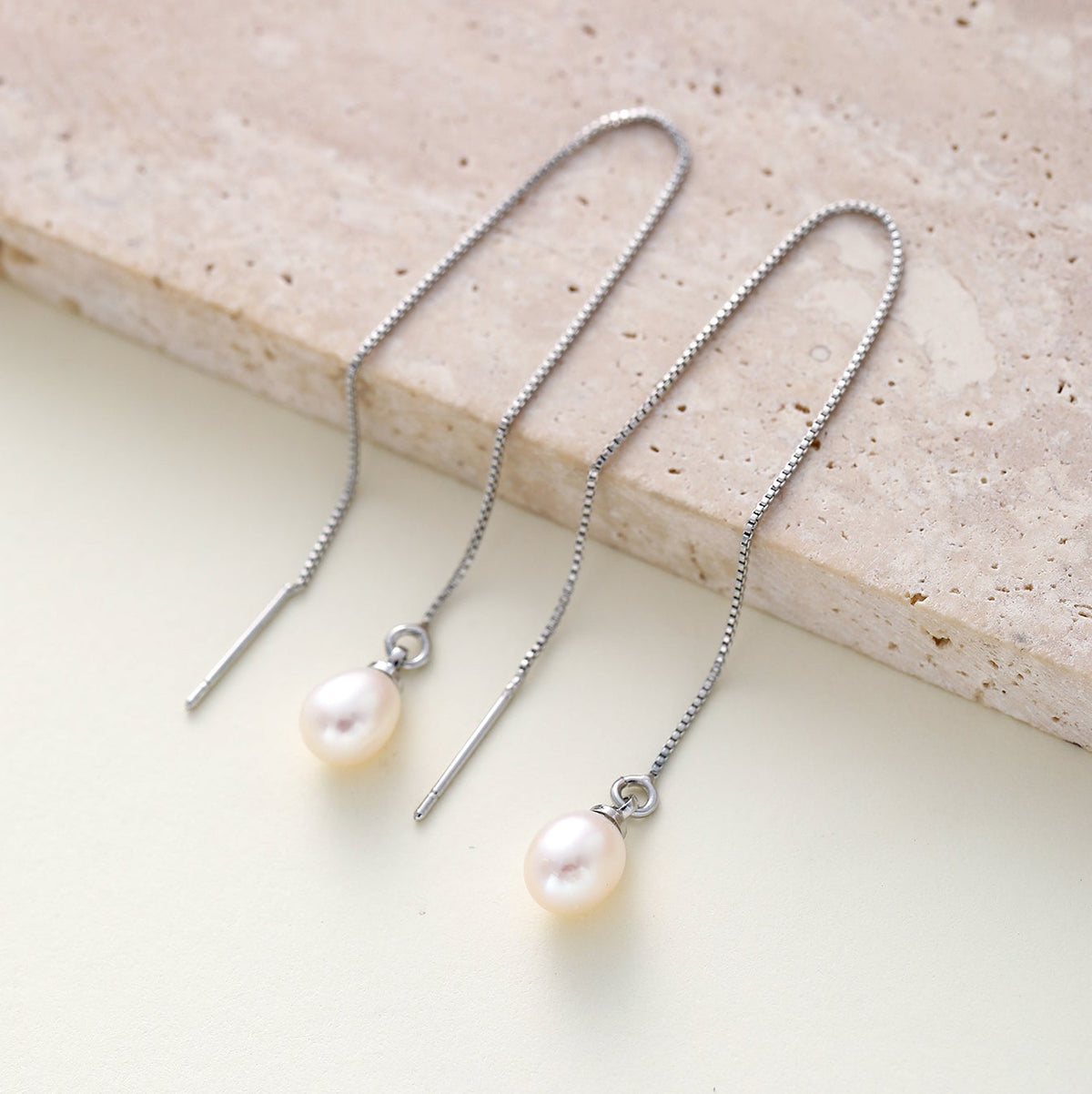 A pair of silver-toned drop earrings with textured chain backs and oval white freshwater pearls