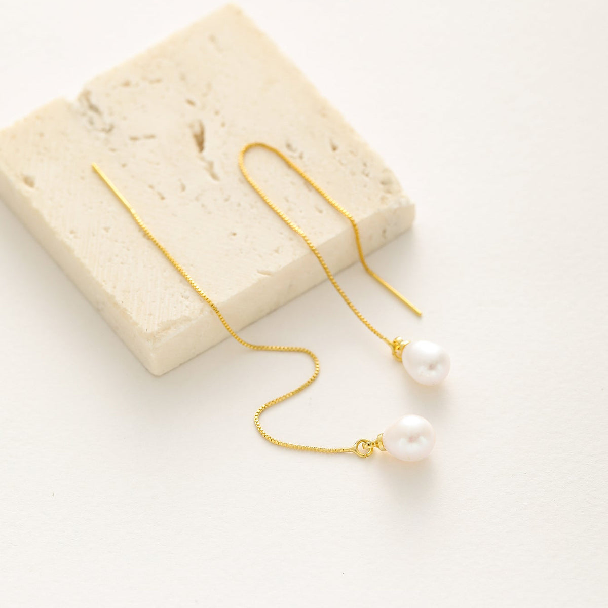 A pair of gold drop earrings with white pearl beads