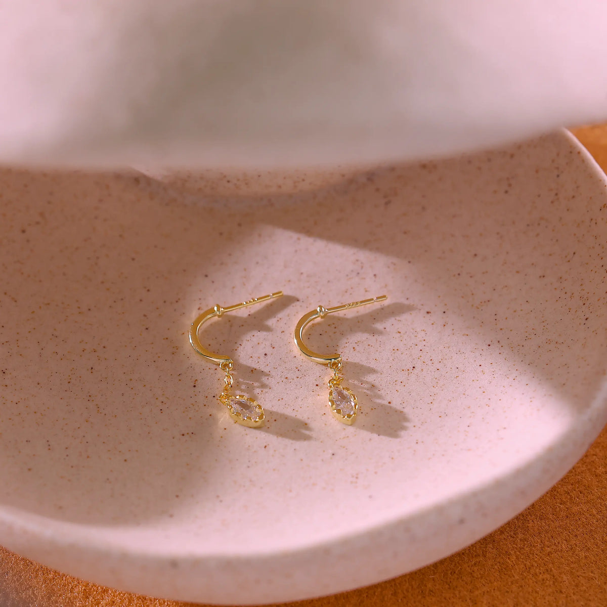 Macro shot of the clear marquise crystal suspended from a gold stud post.