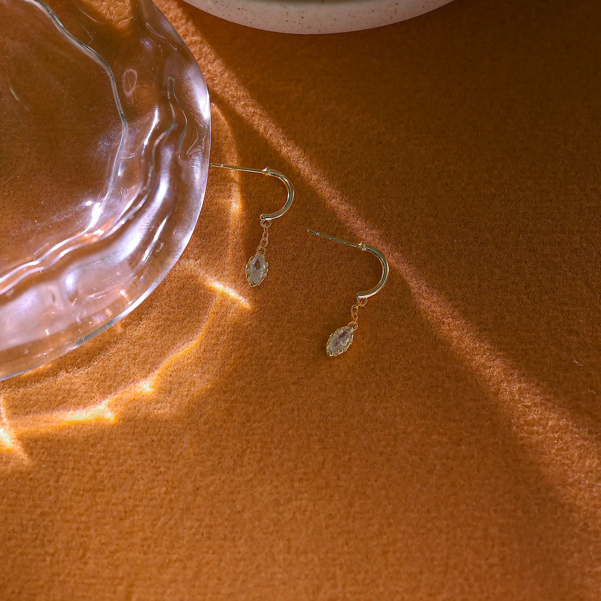 Angled view of diamond drop earrings catching the light on a brown background