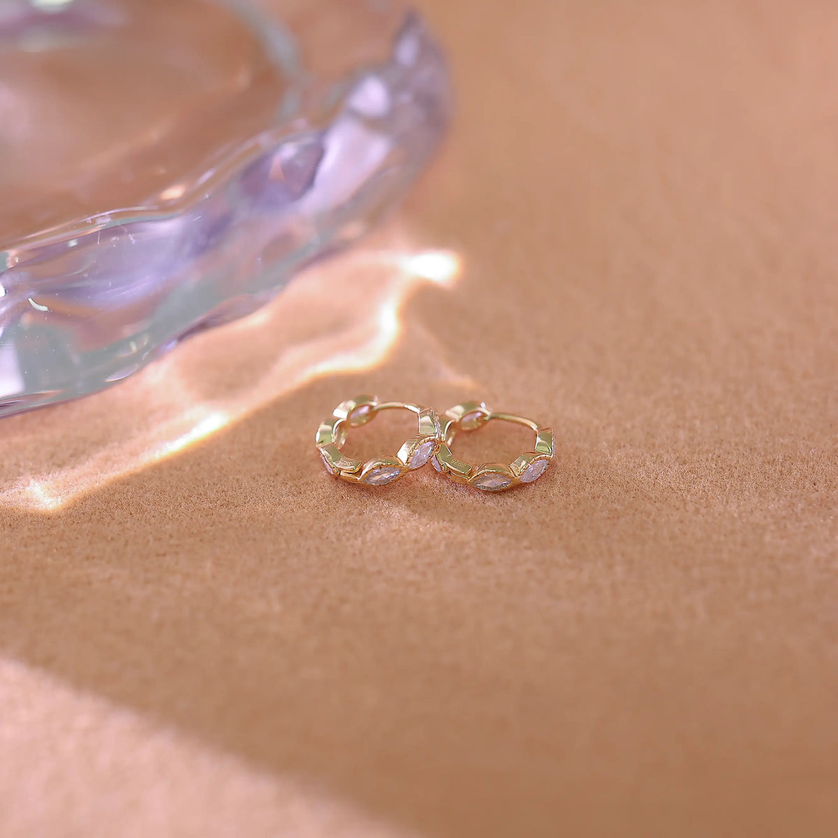 Front facing view of gold hoop earrings showing the jagged, scalloped edge created by the marquise cut diamonds