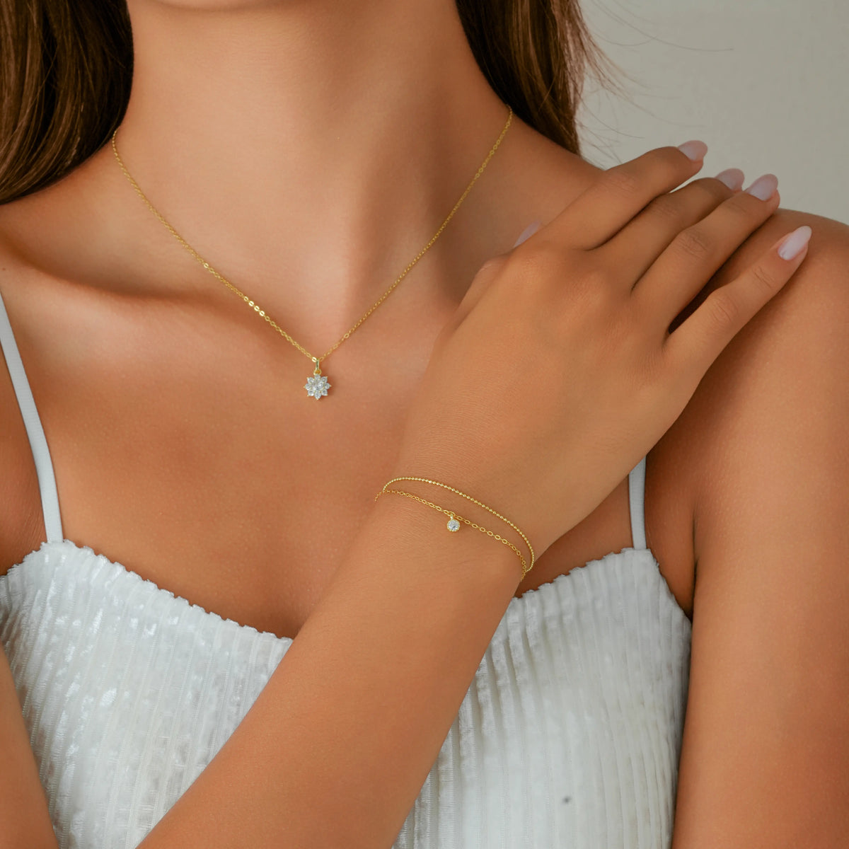 Model wearing a matching 14k gold vermeil jewellery set by Dialuxé. She styles the Pave Snowflake Pendant Necklace layered with a delicate Double Chain Bracelet. Elegant winter gift set for women.