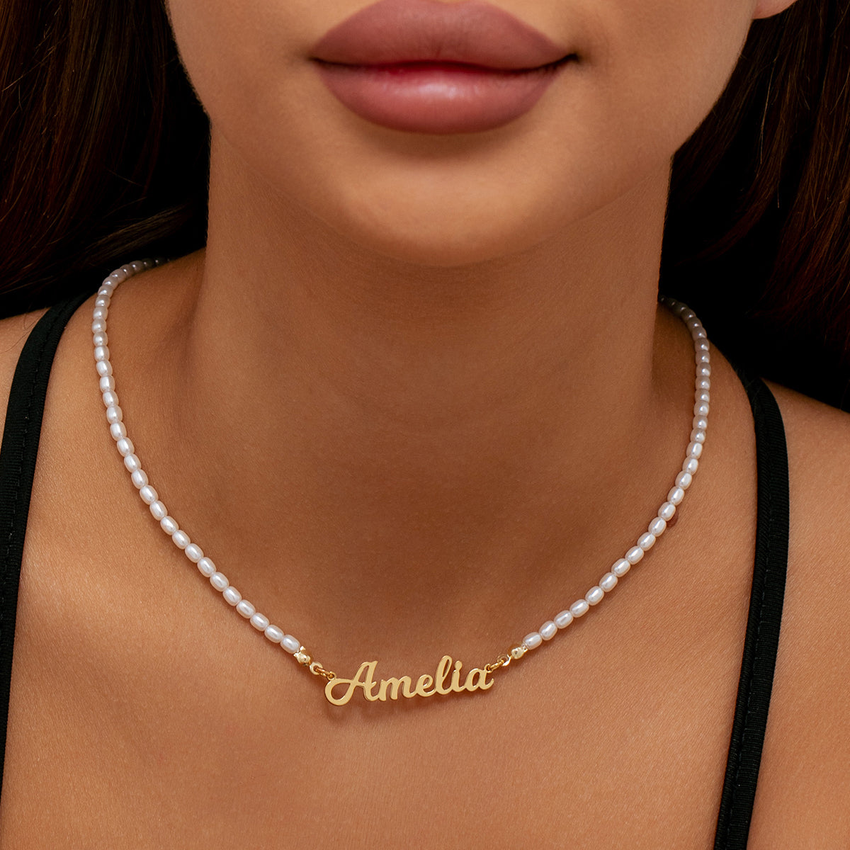 A close-up of a model wearing a custom name necklace beaded pearls chain