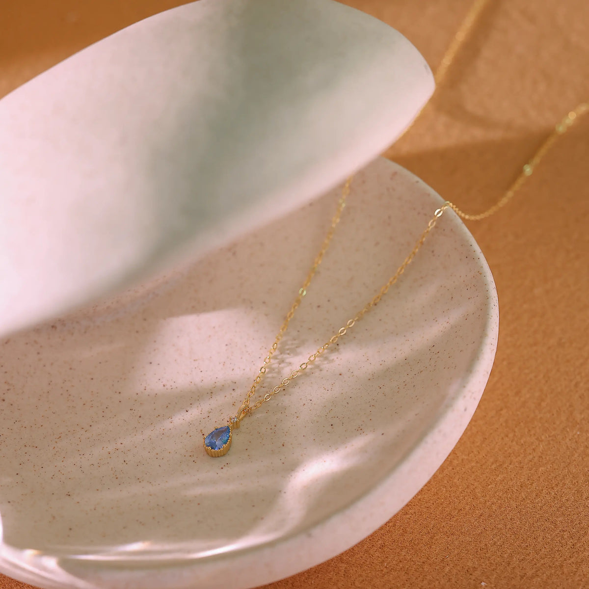 Delicate gold cable chain attached to the blue crystal pendant.